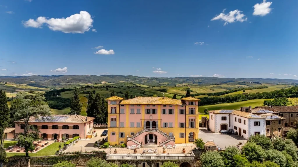 Villa storica con paesaggio collinare toscano sullo sfondo.