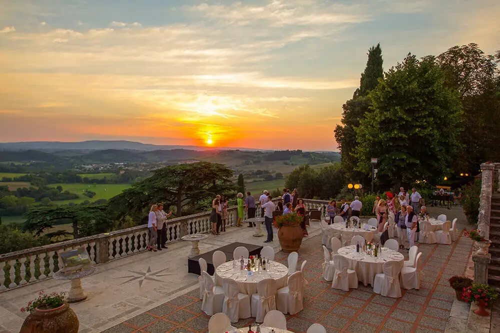 Tramonto su terrazza con tavoli e persone all'aperto.